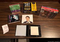 All items laid out on tabletop showing game box, DVDs, CDs and open case