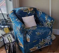 Blue floral slipcovered chair with white pillow and swivel base visible