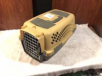 Full view of assembled beige and gray plastic pet carrier with metal door