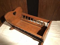 Wooden doll cradle showing heart cut-out, spindle sides, rocker runners