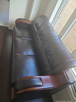 Top angled view of entire sofa showing faux leather upholstery and wooden arms