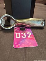 Full view of metal bottle opener showing overall form and drilled hanging hole
