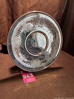 Front view of round silverplate tray showing pierced rim and etched floral pattern