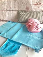 Blue changing pad, pink knot pillow and gray support pillow displayed together
