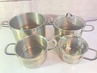 Front view of four ELO stainless steel pots and two glass lids