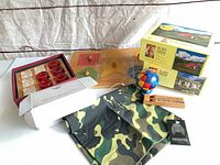 Group shot of all items including jigsaw boxes, tic-tac-toe, wood puzzles, puzzle ball, bandana