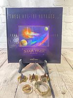 Group shot showing pop-up album book standing on easel with pins, coin and watch in foreground