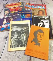 Group shot showing all eight Star Trek related magazines, books and fanzines spread on wooden surface