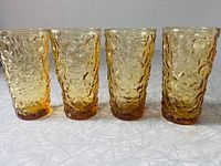 Front view of all four honey-gold textured tumblers