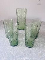 Five green textured tumblers arranged on table