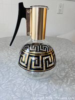 Front view of glass carafe showing Greek key pattern and gold collar
