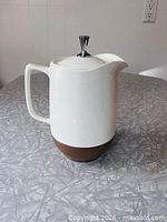 Full front view showing two-tone body, handle, spout and lid