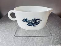 Side view of milk glass gravy boat on acrylic riser showing Old Town Blue pattern and overall condition