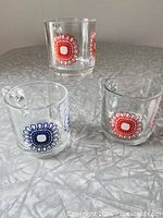 All three clear glass sunflower-pattern mugs on tabletop