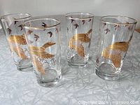 Four Dominion Glass tumblers showing gold geese motif and rims