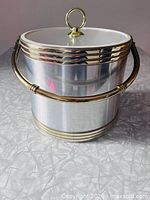 Front view of ice bucket showing chrome body, gold bands, handle and lid