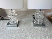 Both lamps showing acrylic columns, chrome bases, white shades