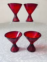 Front view of all four ruby red cocktail glasses, two elevated to show shape