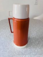 Full view of brown Thermos flask with cream lid and base