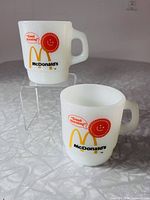 Two white milk glass McDonald's Good Morning mugs on display stand