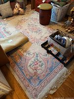 Large rectangular floral rug with fringe and surrounding objects