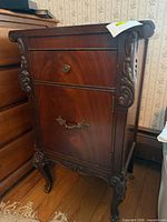 Front view of side table cabinet showing drawer, door, carving, legs