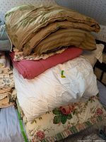Stack of assorted comforters showing multiple patterns and colors