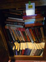 Shelf showing large quantity of assorted books stacked vertically and horizontally