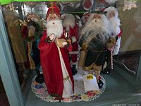 Group of five Byers' Choice Santa figurines in display case