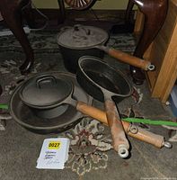 Group of cast iron pans and lids showing all items in lot