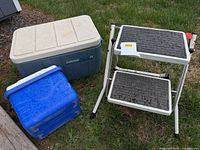 Two coolers and folding step stool on grass