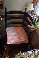 Full view of black painted wooden corner chair placed in room