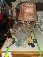 Group shot of lamp, glass basket, carafe and rooster items on tabletop