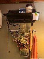 overall view of wall shelf, crock, print, iron hooks, floral sconce and candles