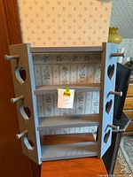 Full view of blue wall shelf showing shelves, heart cut-outs and side pegs