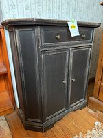 Front view of black distressed cabinet showing drawer, doors, and hardware