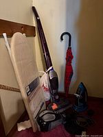 Group shot showing vacuum, ironing board, umbrella, iron, charger