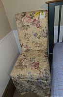 Full view of floral upholstered side chair next to bed