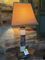 Full view of lamp on patio, showing marble column, shade, base