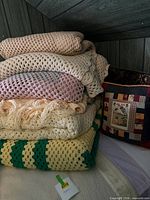 Stacked afghans showing colors and patterns with pillow as background