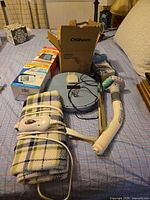 Lot overview showing garment steamer box, blood pressure monitor box, blue disc pad, back massager, heating pad, ice bags