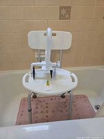 Shower chair placed in bathtub with safety rail handle resting on seat