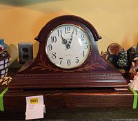 Front view of wooden mantel clock showing dial and decorative inlay