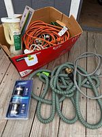 Overview of lot showing garden hose, cords, zip ties container and box of extension cords