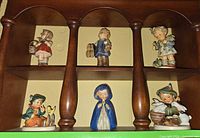 Full view of six Hummel figurines displayed on shelf