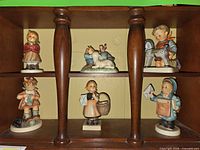 Front view of six Hummel figurines on shelf