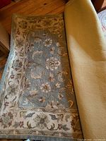 Full view of rug partially rolled showing blue field and floral border