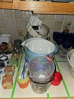 Overall view of assorted mixing bowls, measuring cups, spice jars, colanders, Bundt pan and goblets