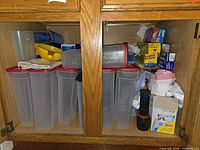 Overview of cabinet showing Rubbermaid containers, boxed food bags, mixing bowl and towels
