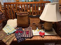 Group shot of lamp, baskets, textiles, pillow and tray on bench